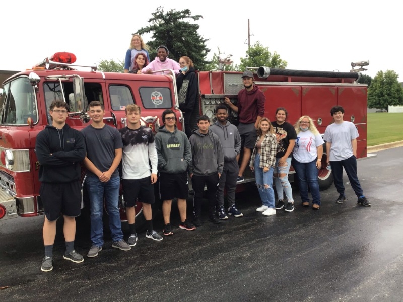 Fire Rescue Students surrounding fire engine.